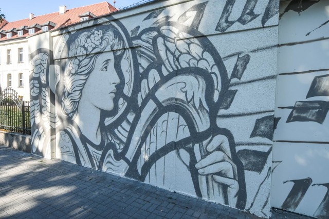 Przy ul. 20 Stycznia w Bydgoszczy powstaje właśnie nowy mural - charakterem nawiązuje do tego, który już tam był, ale będzie nieco inny. Prace nad malowidłem trwają nocami. Zobaczcie, w tej chwili wygląda nieukończone jeszcze dziełoWcześniej przy ul. 20 Stycznia, na ścianie w pobliżu Akademii Muzycznej, także można było podziwiać anioły. Niestety, mural padł ofiarą wandali. Teraz trwają prace nad nowym malowidłem - znajdą się na nim również anioły, a prócz tego także pięciolinie i zapis nutowy. Mural tworzy Julian Nowicki, absolwent Akademii Sztuk Pięknych w Krakowie. Niedawno stworzył mural poświęcony Marianowi Rejewskiemu przy ul. Gdańskiej. Po ukończeniu malowidła na 20 Stycznia (nad którym pracuje nocami - obraz przenoszony jest na ścianę za pomocą specjalnego rzutnika), rozpocznie prace przy ulicy Cieszkowskiego - tam z kolei ma powstać mural Józefa Święcickiego.Mural przy 20 Stycznia na koniec zostanie zabezpieczony specjalnym lakierem, który utrudni wandalom zamalowywanie obrazu. Całość ma być gotowa w przyszłym tygodniu.Tutaj obejrzysz najciekawsze bydgoskie murale:Bydgoszcz muralami stoi. Zobacz najciekawsze malowidła w mieście [zdjęcia]