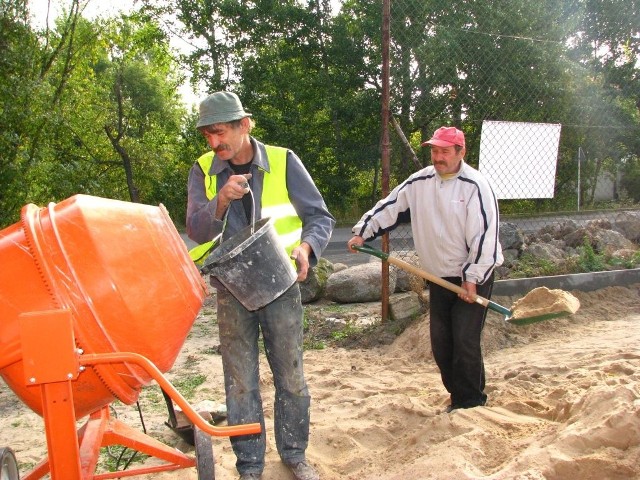 Tadeusz Jankowski (pierwszy od lewej) i Piotr Zażdżyk ze spółdzielni "Pomocna dłoń" budują właśnie chodnik w Dąbrówce 