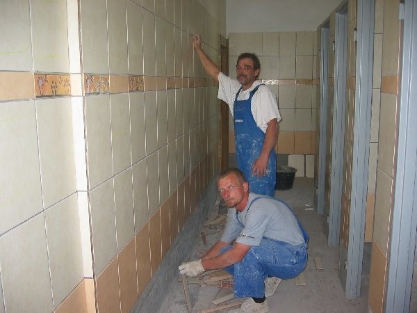 Grzegorz Dembski i Wiesław Grochowalski z  rypińskiej firmy "Instalator" kładą glazurę w  jednej ze szkolnych łazienek.