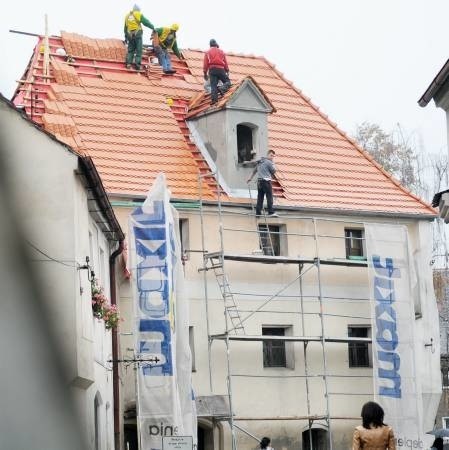 Na dachu baszty uwijają się pracownicy, którzy kładą nową i ładną dachówkę