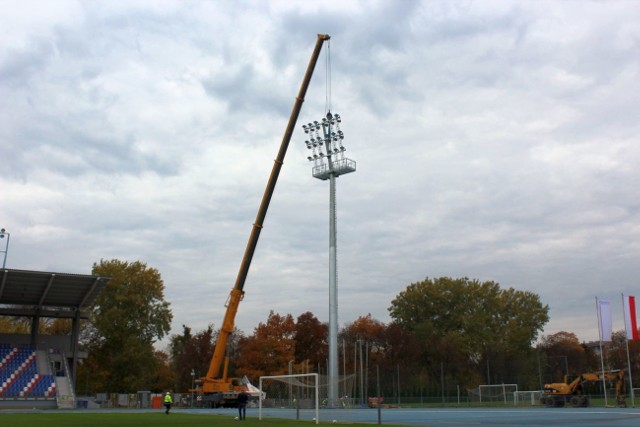 Na stadionie przy ul. Narutowicza 9 we wtorek rozpoczęto stawianie masztów oświetleniowych! Poteżny dźwig podnosił kolejno cztery zmontowane wcześniej 35-metrowe maszty. Firma Ada Light bardzo profesjonalnie postawiła słupy oświetleniowe. Druga ekipa z kolei montowała lampy na dachu trybuny od strony ulicy Narutowicza. Na słupie od strony parku przymocowano też trzy lampy skierowane na boisko treningowe. Jeśli wszystko pójdzie zgodnie z planem, oświetlenie o natężeniu 2000 luxów spełniające wymogi ekstraklasy, powinno działać 10 listopada. 