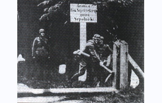 Wczesnym rankiem 1 września 1939 r. wojska niemieckie przekroczyły granice powiatu sępoleńskiego, rozpoczynając II wojnę światową. Fotografia przedstawia niszczenie szlabanu granicznego wykonana w kilka godzin po przejściu wojsk generała Guderiana, pod potrzeby propagandowej niemieckiej kroniki.