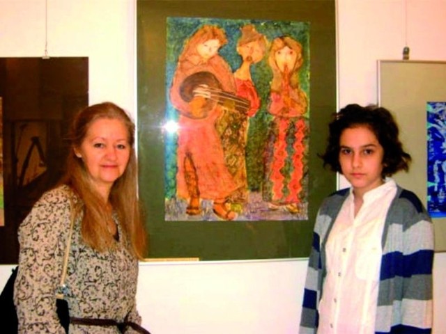 Marcelina Markowska (z prawej) i jej opiekunka Anna Bureś na tle obrazu, który zdobył III miejsce na ogólnopolskim konkursie plastycznym &#8222;Twórczość Plastyczna Inspirowana Muzyką Dawną&#8221;