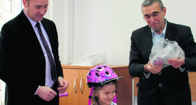 Wójt Przemysław Łysak i  przewodniczący rady gminy Janusz Bednarz przekazują siedmiolatce rower i kask.