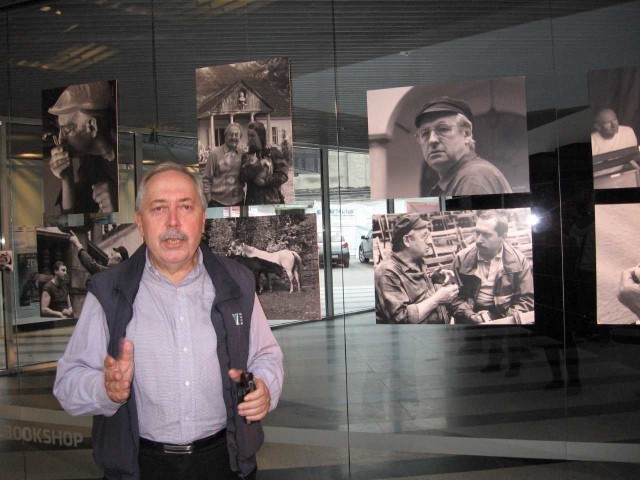 Czesław Czapliński na tle swoich fotografii Andrzeja Wajdy.