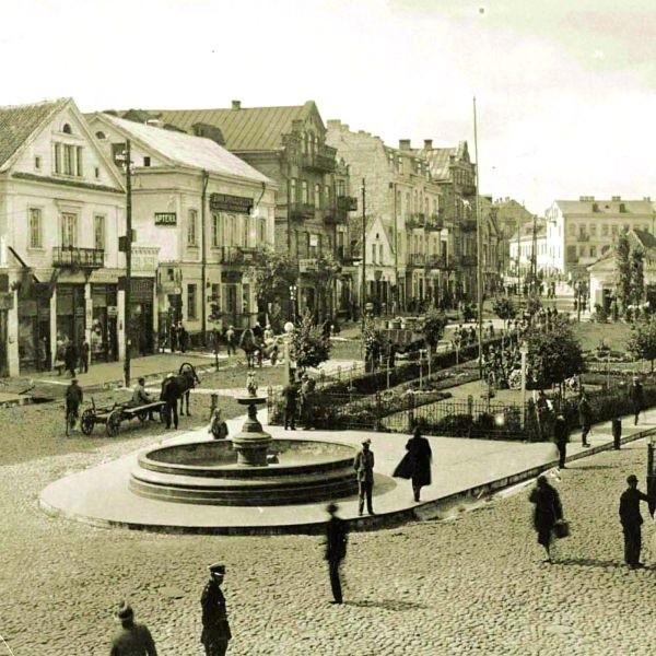 Ok. 1930 r. Południowa pierzeja rynku. Od lewej strony kamienice: Szabryńskiego, w niej była restauracja "Madera&#8221;, Chany Karafiol i Pauliny Wilbuszewicz, która z mężem Eugeniuszem prowadziła aptekę, Borucha - Szmula Kwarta, w której znajdowała się kolejna restauracja "Łącz&#8221;, prowadzona przez Krauzego.