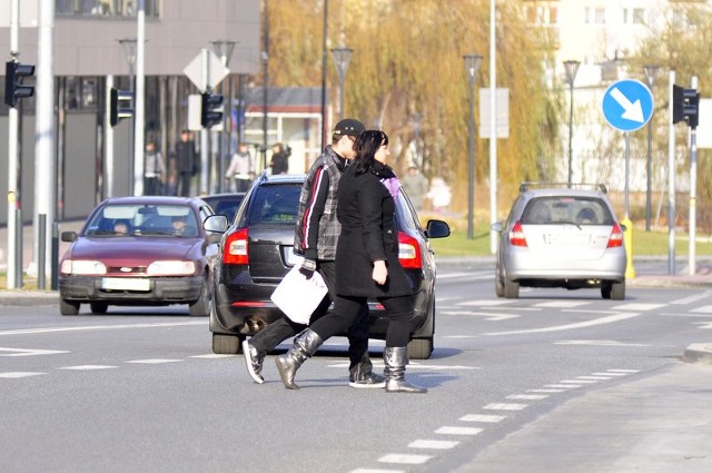 Parami, niespiesznie, łamiąc przepisy, ludzie przechodzą przez ulicę Chrobrego.