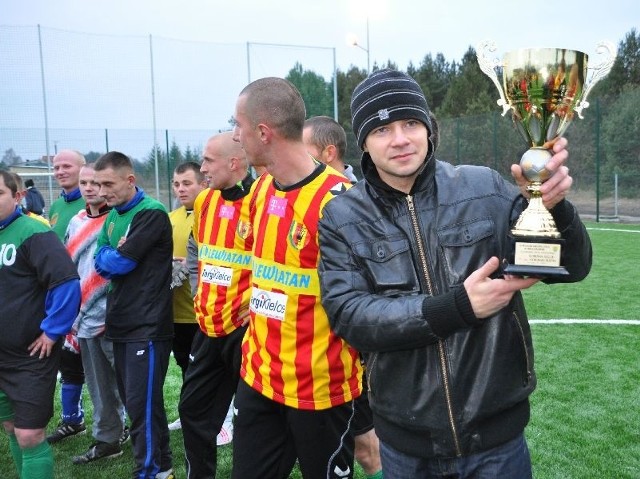 Kapitan Korony Kielce Kamil Kuzera prezentuje puchar, jaki klub otrzymał za udział w otwarciu Orlika 2012 w Mroczkowie.