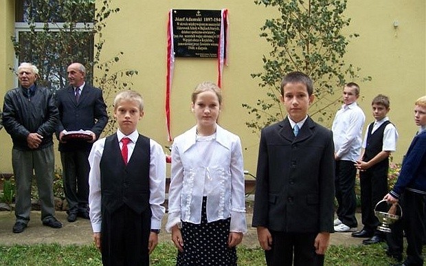 Uczniowie szkoły podstawowej w Bajkach Starych przed odsłoniętą tablicą