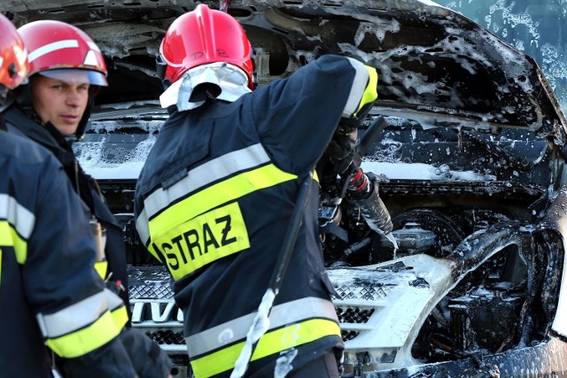 Strażacy gaszący pożar auta.