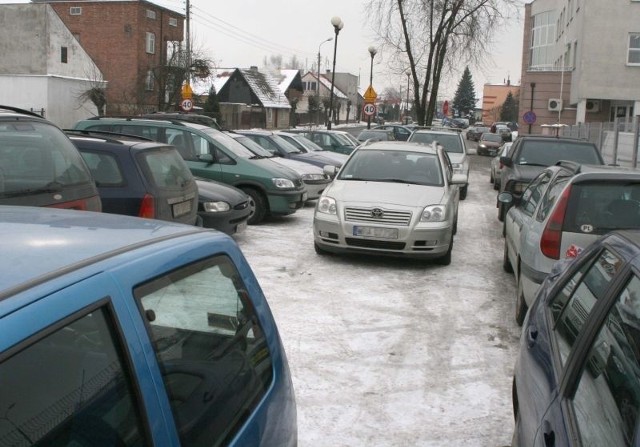 Wiele samochodów stoi zaparkowanych na środku parkingu i blokuje wyjazd innym.