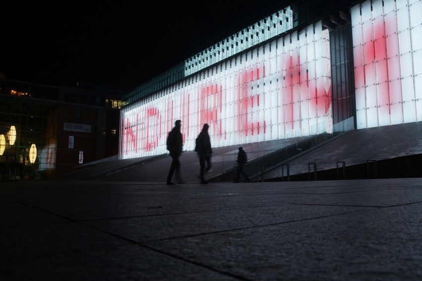  Fasada Centrum Spotkania Kultur w Lublinie podświetlona hasztagiem #Muremzapolskimmundurem        