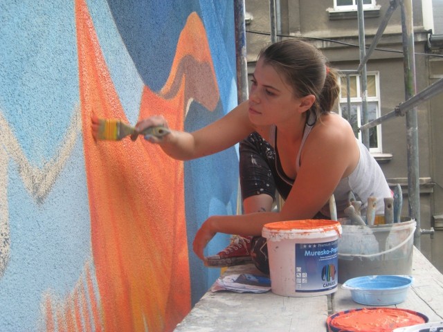Anna Taut maluje na ścianie kamienicy przy ul. Drzymały