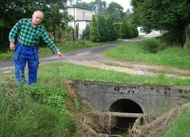 Mieszkaniec Bulowic Anzelm Kiepura pokazuje rurę osłonową kabli teletechnicznych przed  przepustem drogowym. Co jakiś czas po ulewie jest ona  przyczyną podtopień  jego i sąsiednich posesji