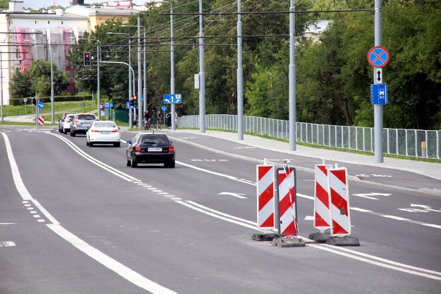 Ul. Muzyczna. Ubytek w asfalcie, czyli dziura na nowej jezdni zabezpieczona taśmami i słupkami