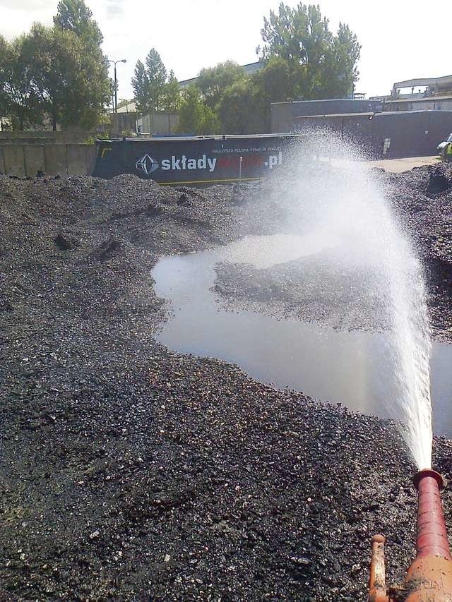 Z rozwiniętego na hałdzie węgla węża leje się strumieniem woda, potem na mokrą hałdę trafia drobny kamień z kruszarki. To wszystko się miesza i towar zyskuje na wadze...