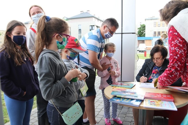 Renata Piątkowska rozdaje autografy przed biblioteką po spotkaniu z małymi czytelnikami