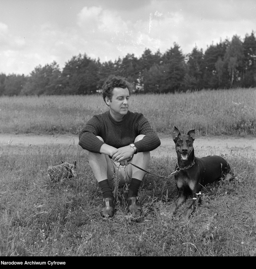 Krzysztof Orzażewski siedzi na trawie. Obok pies rasy...