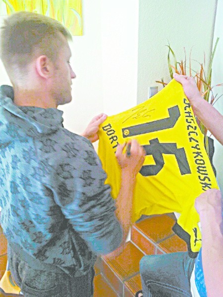 Jakub Błaszczykowski podpisuje przekazaną na licytację własną koszulkę Borussi Dortmund.
