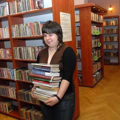 Bibliotekarka-stażystka Marta Niemczyk musi znaleźć miejsce dla nowych książek na bibliotecznych półkach