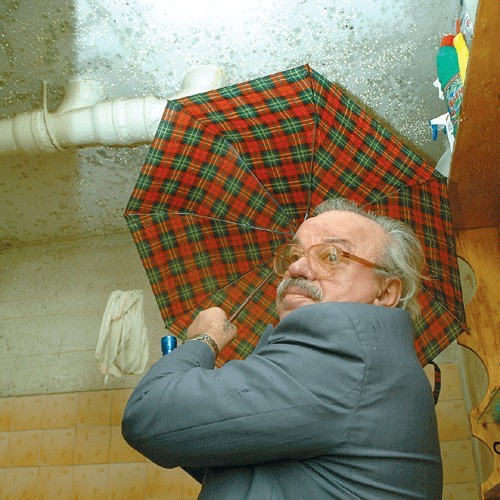 Zdzisław Żak w swojej łazience. Z opuszczonego mieszkania piętro wyżej bez przerwy leje się woda na całej powierzchni syfitu.