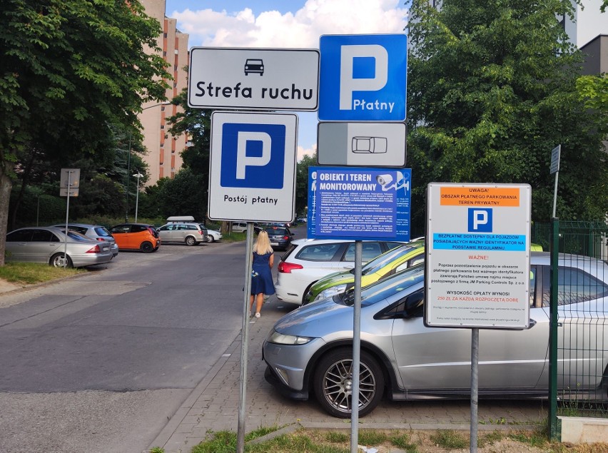 O tym, że parkowanie jest płatne informuje ściana tablic i...