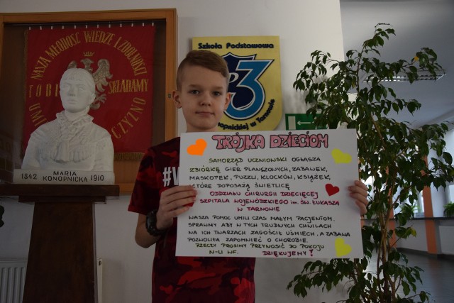 Mikołaj Szeląg z plakatem, poprzez który udało się zachęcić wielu uczniów „trójki” do umilenia czasu małym pacjentom