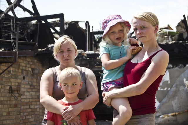 Paula Wroniak i Anna Marcinkowska wraz z dziećmi. Z tyłu ich spalony dom.