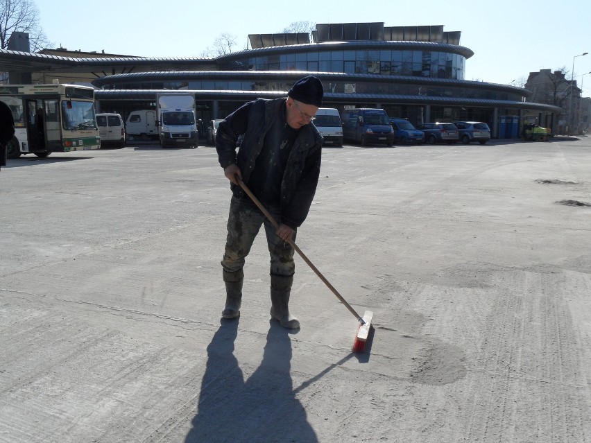 Robotnik czyści nawierzchnię placu manewrowego przed halą...