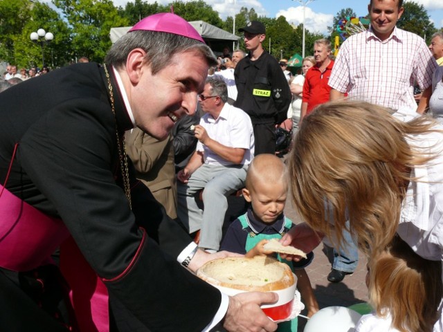 Biskup Krzysztof Nitkiewicz częstuje gości chlebem.