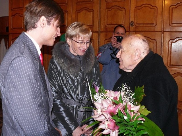 Urodzinowe księdzu infułatowi składa Beata Gosiewska. Obok Maciej Pieńkowski, jej asystent.