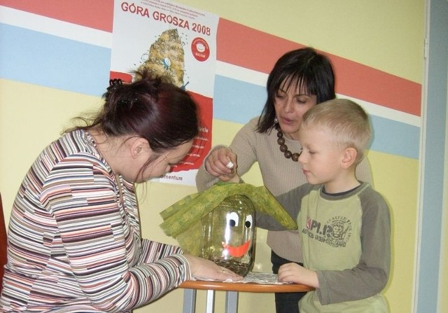 Joanna Kulasiewicz i Katarzyna Grzwyan z przedszkola numer 9. W środku przedszkolak Marcinek wrzuca swój grosik.