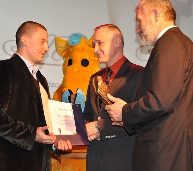 Mistrz karate kyokushin Mateusz Garbacz otrzymuje statuetkę od posła Lucjana Pietrzczyka i burmistrza Michała Cichockiego