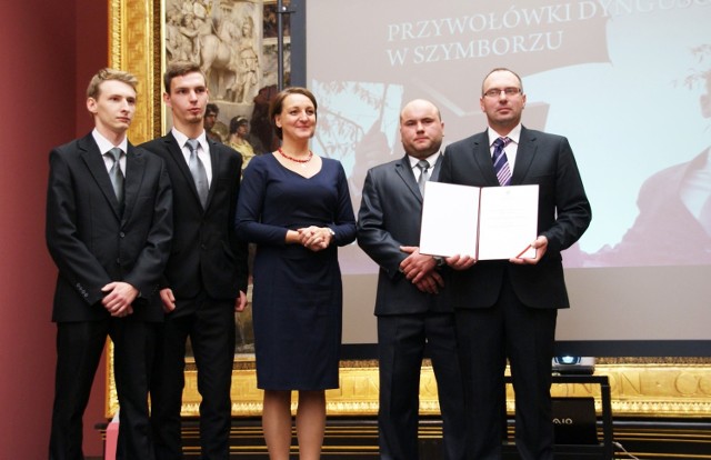 Paweł Małachowski (po prawej) prezentuje dokument potwierdzający wpisanie przywołówek na Krajową Listę Niematerialnego Dziedzictwa Kulturowego
