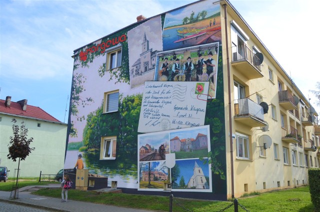 I ostatni, najnowszy, pojawił się na ścianie bloku przy ratuszu dość niedawno, bo w październiku. Cała boczna ściana 2-piętrowego budynku została ozdobiona kolorowymi malunkami, które przedstawiają łódkę płynącą przez jezioro otoczone lasem oraz pocztówki, a na nich ratusz, zespół śpiewaczy oraz... kartka napisana w języku niemieckim. Mural musiał mieścić sie w wyznaczonych ramach projektu euroregionalnego, co oznacza, że musiał nawiązywać do współpracy Kargowej z niemieckim miastem Schulzendorf, dlatego należało zawrzeć akcenty tej gminy partnerskiej.