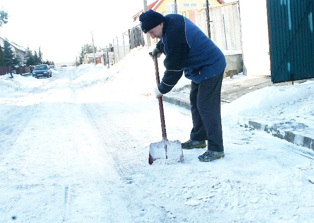 Pan Stanisław odśnieża teren przed garażem. Ulica Dąbrowskiej jest położona niżej, niż sąsiednie, kałuże pojawiają się tu bardzo często.