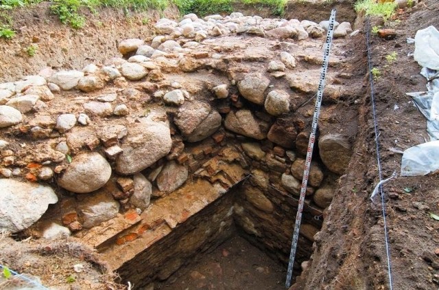 Fragment fundamentów kamienicy. Jeden z dwóch budynków murowanych, o których wspominają inwentarze z XVII wieku. Zostały one odkryte przez archeologów w 2006-2007 roku. Na lotniczym zdjęciu widać rzut tych fundamentów. 