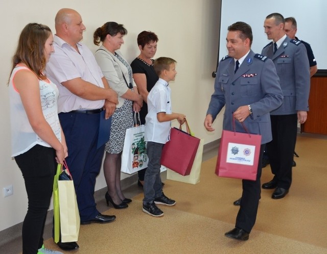 Martynie Nowak (z lewej), Sebastianowi Michalskiemu oraz ich rodzinom gratuluje komendant szydłowieckiej policji, młodszy inspektor Jacek Różański (na pierwszym planie).