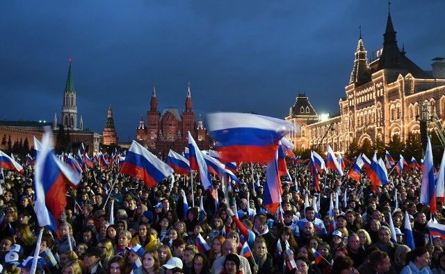 Wiec poparcia dla Putina na Placu Czerwonym. Nagrania wykonane bezpośrednio na Placu Czerwonym wskazują, że uczestnicy wiecu w większości nie reagowali na bojowe okrzyki ze sceny. Tłum stał biernie trzymając flagi Rosji, które wcześniej były rozdawane przez rozstawionych przy wejściu wolontariuszy