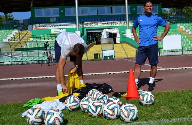 Asystent trenera Jacek Paszuklewicz (schylony) i Sebastian Łukiewicz, trener bramkarzy przygotowują sprzęt do treningu