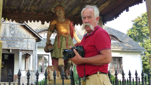 Francois Poche przy figurze świętego Floriana, stojącej przed zabytkowym dworkiem w Mostkach.