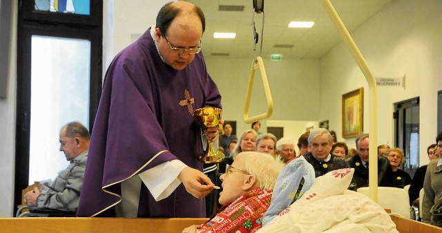 Ksiądz Adam Trzaska udziela komunii podopiecznym hospicjum