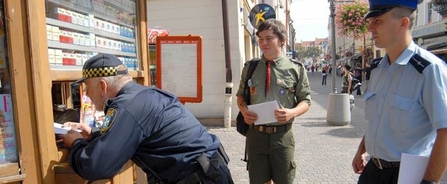 Sierżant Komendy Miejskiej Policji Ryszard Dziura, strażnik miejski Bogusław Reguła i harcerz Michał Lachowicz pouczają sprzedawców, jakie grożą konsekwencje za sprzedaż papierosów nieletnim.