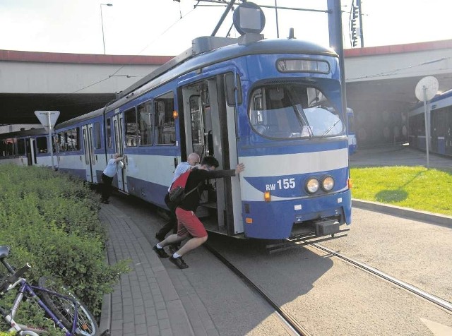Pasażerowie pomagają motorniczemu pchać tramwaj na rondzie Mogilskim