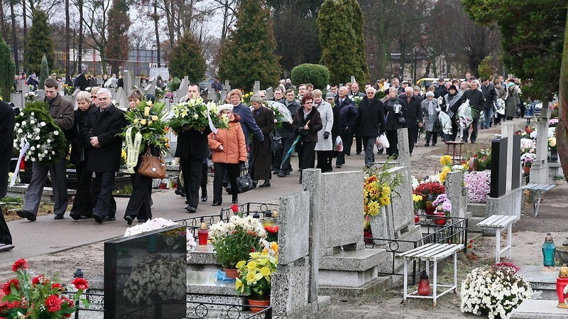 Kondukt żałobny kroczy uliczką cmentarza parafialnego przy...