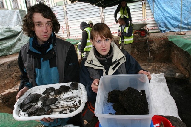 Michał i Nina Glińscy prowadzący badania na placu św. Tekli pokazują fragmenty naczynia i bryłki ziemi z ziarnem, które przechowywano w garnku.