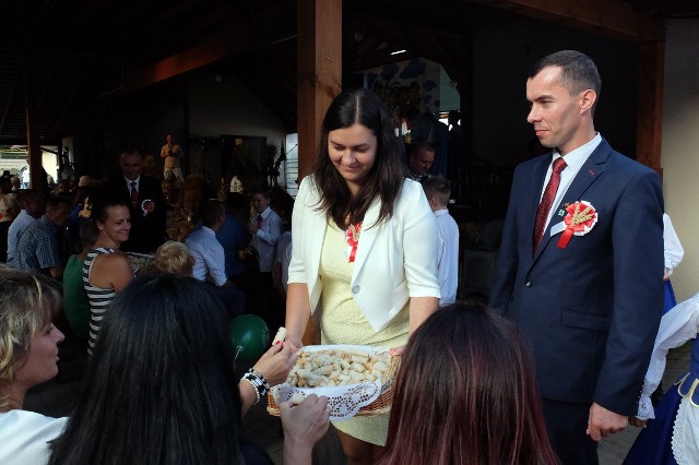 Starostowie powiatowych dożynek Irena Gustyn i Grzegorz Chylewski dzielą się dożynkowych chlebem z mieszkańcami