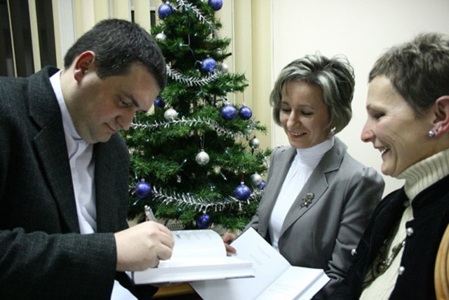 Główny redaktor książki - ks. dr Sławomir Zych podpisuje książkę.