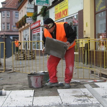 Grzegorz Madziała układa nowe płyty na chodniku przy pl. Przyjaźni. Czy znów zniszczą go parkujące auta?