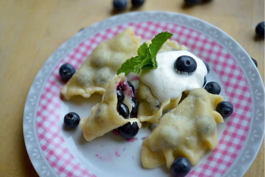 Pierogi z jagodami warto podać z kleksem śmietany...